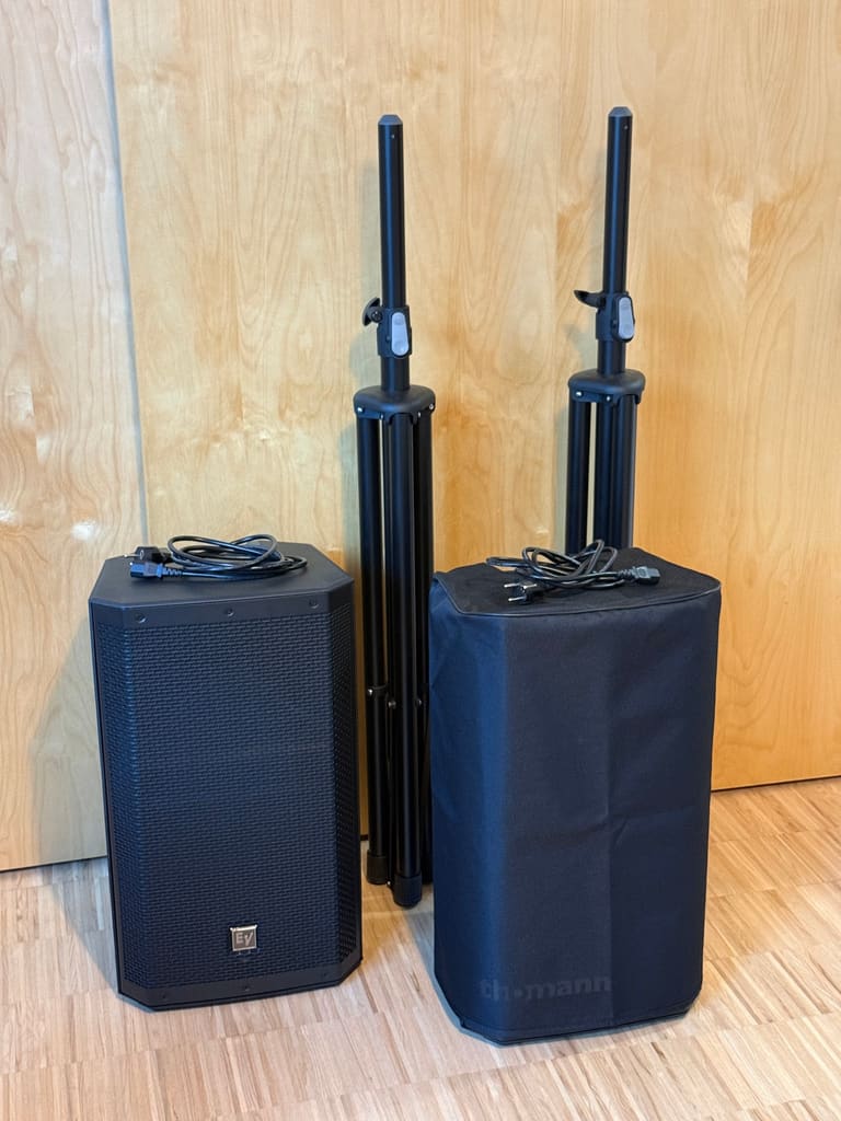Electro-Voice ZLX 12P G2 speaker with power cables, a padded cover and two folded speaker stands